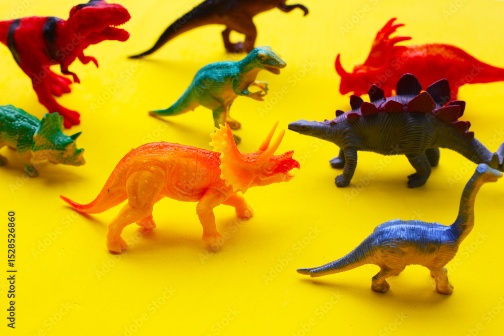 Fototapeta premium Plastic dinosaur toys on yellow background