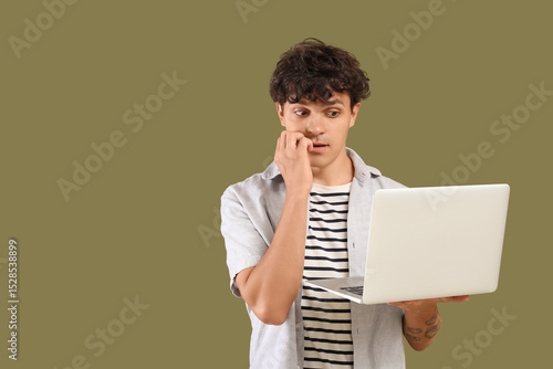 Worried male programmer with laptop on green background