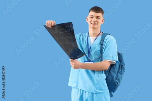 Young male medical student in scrubs holding x-ray image, healthcare educatio...