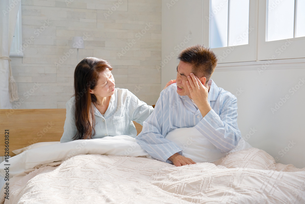 Fototapeta premium ベットの上で頭痛がする中年の男性