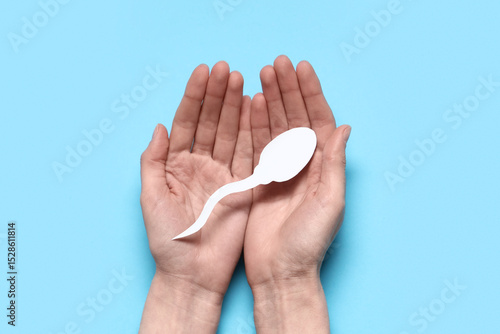 Hands with sperm cell on blue background