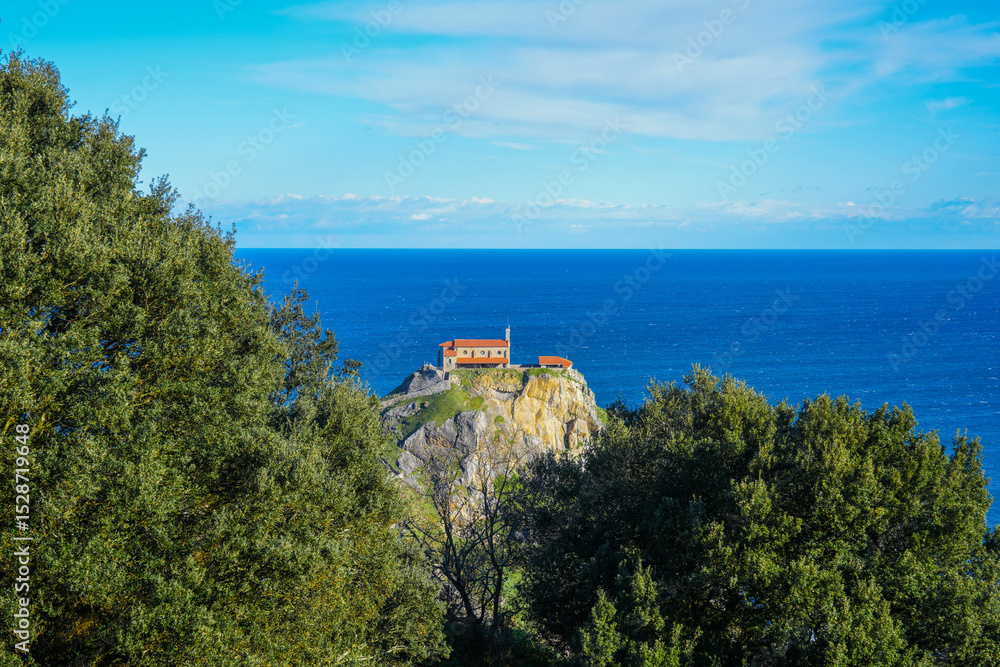 Naklejka premium View through trees of San Juan de Gaztelugatxe church
