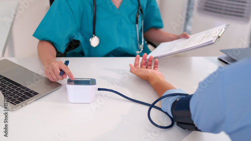 Quadro su tela Asian women doctor measures blood pressure of a patient with electronic device a