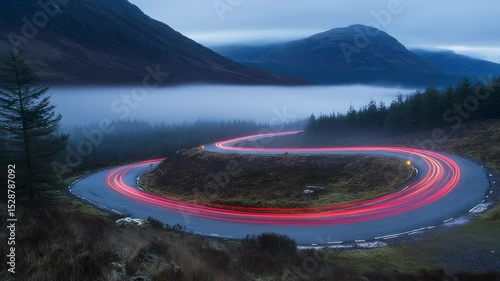 Car light trails on winding mountain road through fog in Scotland UK