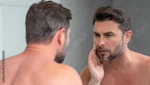 Male beauty cosmetics, beauty and skincare. Morning healthcare and hygiene for man. Perfect beauty skin. Handsome millennial man after shower apply nourishing facial cream or mask on skin.