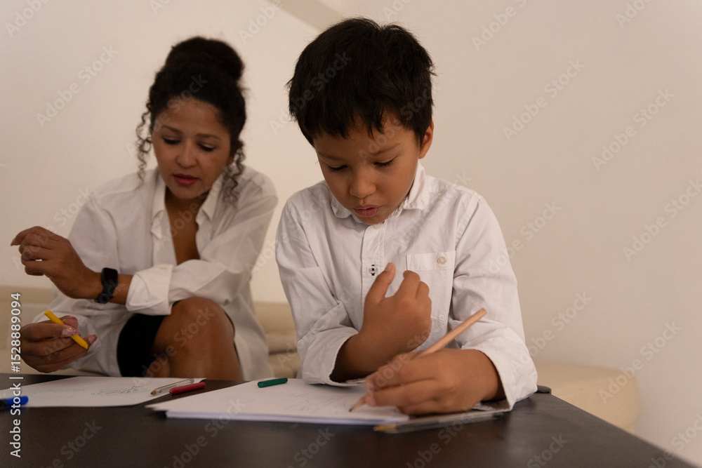 Focused boy drawing with colored pencils while mother watches