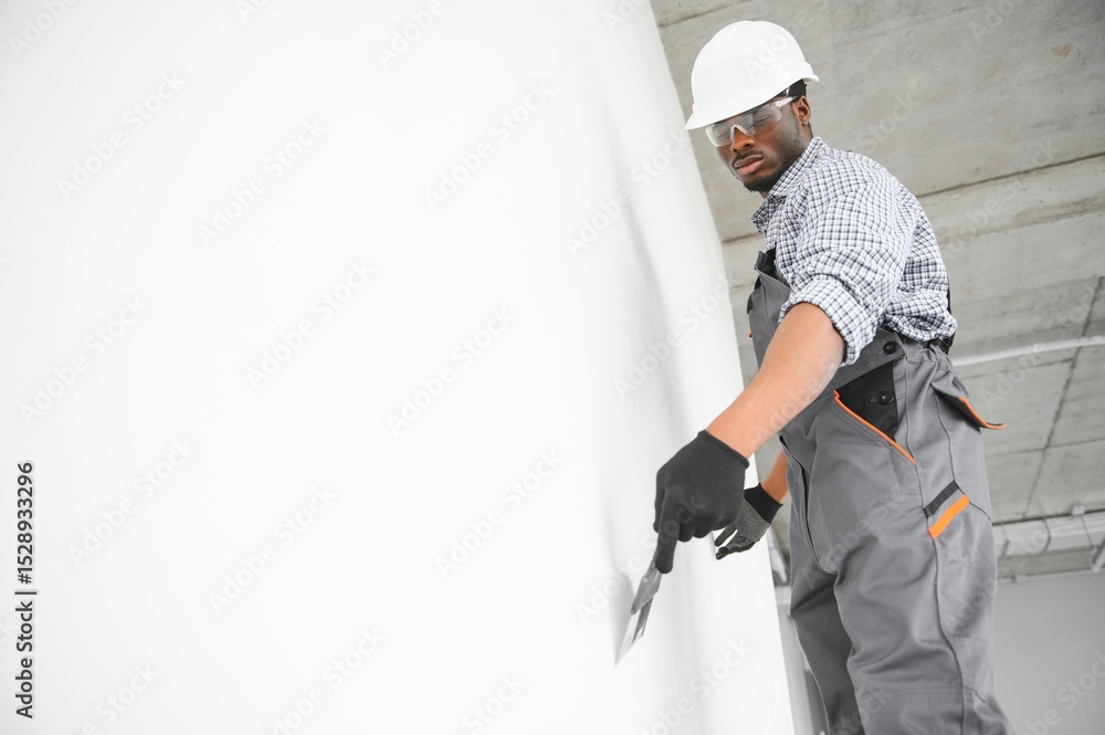 business, building, and people concept. african builder in hardhats with plastering tools indoors business, building, and people concept. african builder in hardhats with plastering tools indoors