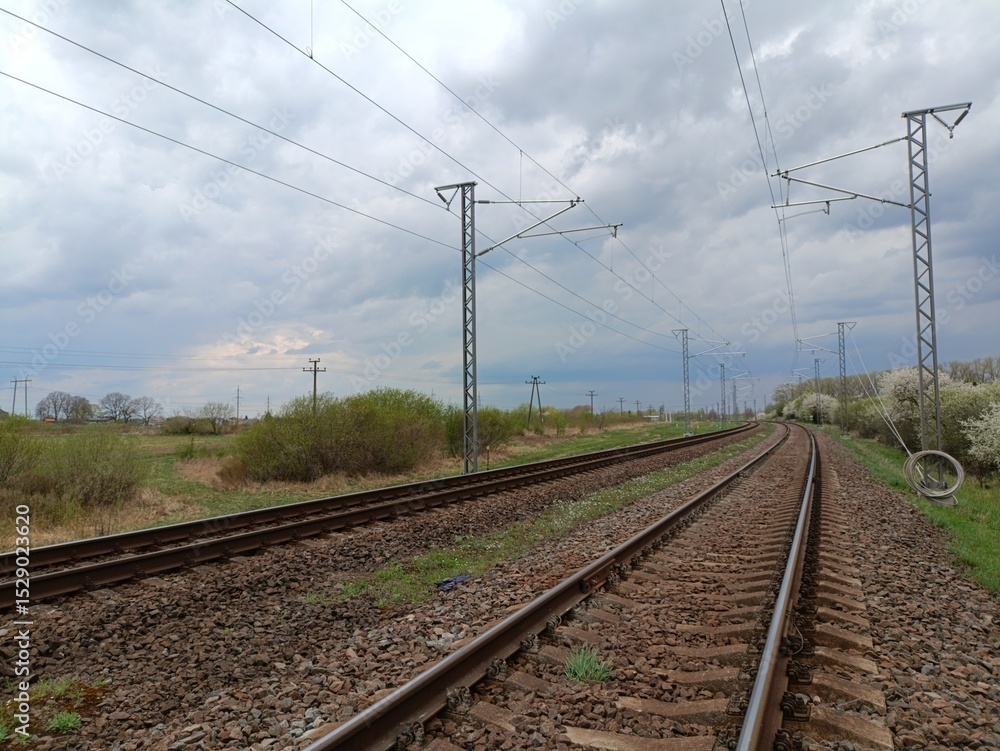 Two way railroad tracks in countryside. Two railway tracks. Cloudy day. Countryside. Fields and trees. Two way railroad tracks in countryside. Two railway tracks. Cloudy day. Countryside. Fields and trees.