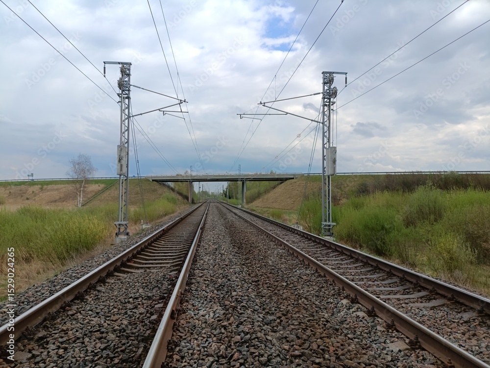 Two way railway tracks and bridge. Two railroad tracks. Concrete bridge. Cloudy day. Countryside. Field and trees. Two way railway tracks and bridge. Two railroad tracks. Concrete bridge. Cloudy day. Countryside. Field and trees.