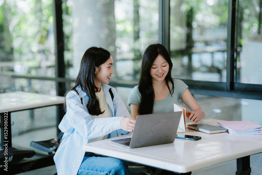 Two female students are sitting in a cafe and working on a school project Two female students are sitting in a cafe and working on a school project