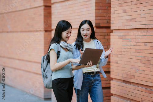 Two happy female students walking on a college campus during break and talking. Copy space.