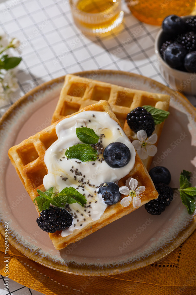 Belgian waffles with blueberries, honey and mint on a white plate. Breakfast with a cup of coffee and sweet waffles. Belgian waffles with blueberries, honey and mint on a white plate. Breakfast with a cup of coffee and sweet waffles.