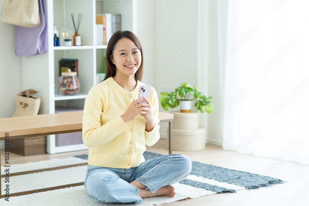リビングでスマホを使う若い女性 リビングでスマホを使う若い女性