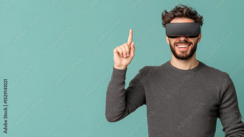 Naklejka premium A man wearing VR headset, smiling and pointing upward against a teal background. He's excited and engaged