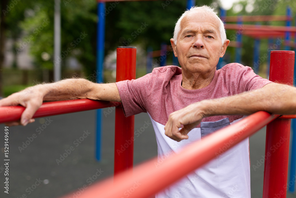 Obraz premium Old man standing between parallel bars outdoors
