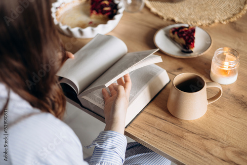 Fotografija Close-up of a woman reading her Bible while having breakfast in a cozy kitchen