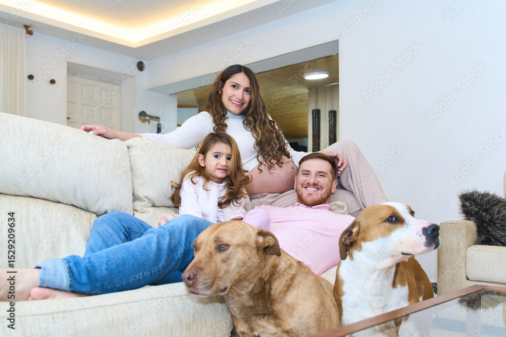 Happy family relaxing on sofa with dogs in living room Happy family relaxing on sofa with dogs in living room