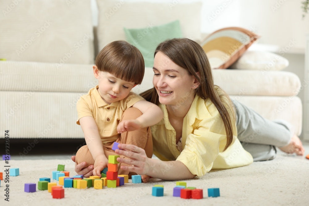 Fototapeta premium Mother and son playing with colorful cubes at home