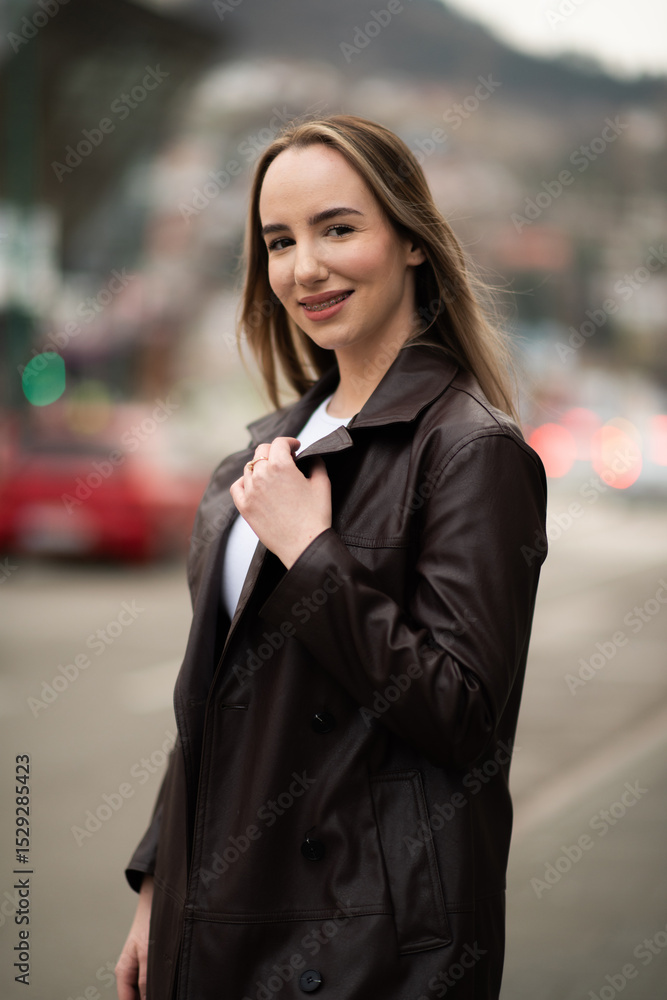 Confident woman standing in leather coat with blurred cityscape Confident woman standing in leather coat with blurred cityscape