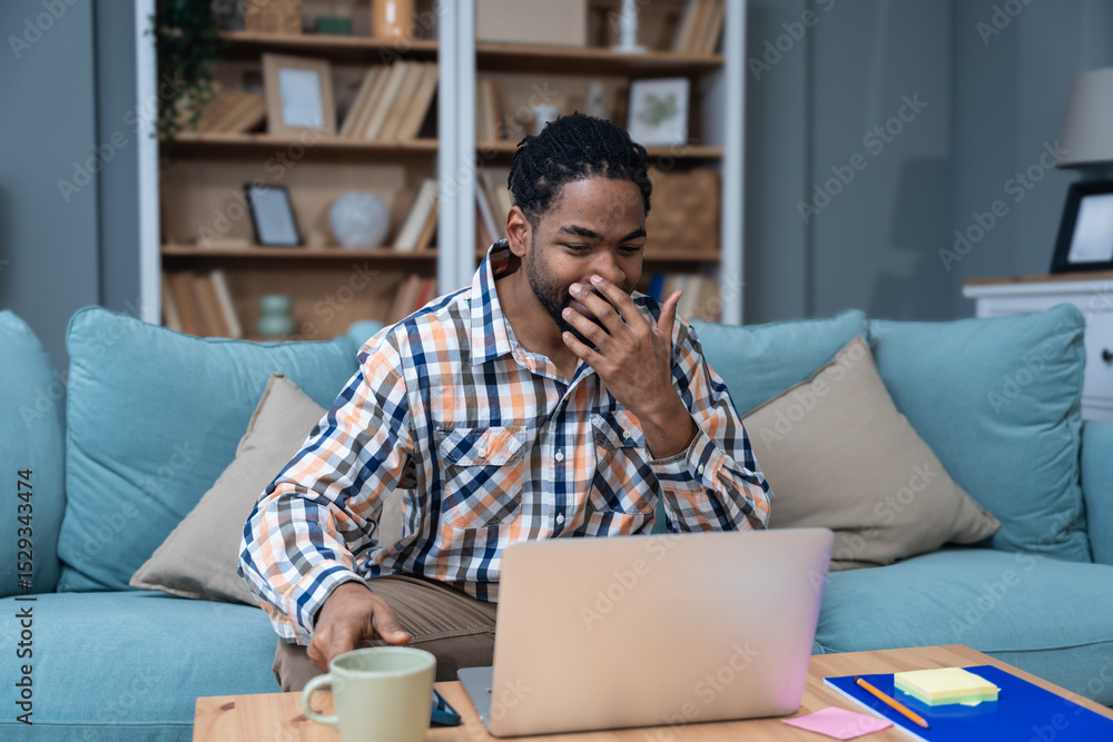 Φωτογραφία Young entrepreneur working from home, planning while reading suggestions on his laptop, enjoying a successful moment in a cozy living room, modern lifestyle and remote business concept