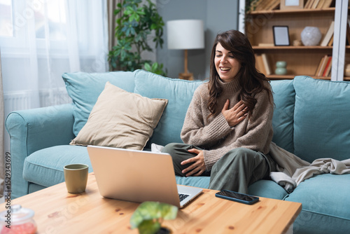 Young woman attending online therapy session from her living room, expressing emotion while talking to a professional therapist, mental health and personal growth support via digital communication.