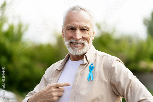 Obraz na płótnie Senior man showing blue ribbon for prostate cancer awareness month