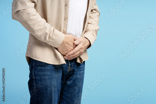 Photos Senior man experiencing abdominal discomfort on blue background