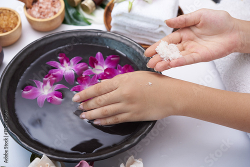Young woman applying natural scrub on hands against white background. Spa treatment and product for female hand spa, massage, perfumed flowers water and candles, Relaxation. Flat lay. top view.