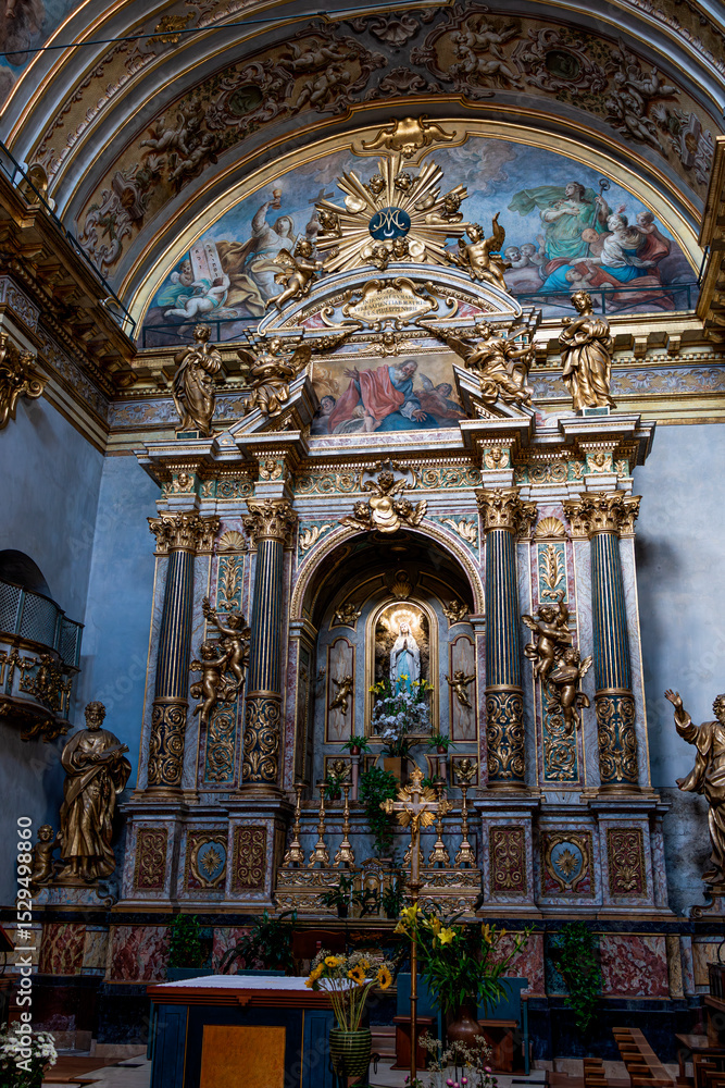 Fototapeta premium A view of the Temple of Minerva and the adjacent medieval clock tower in the historic center of Assisi, under a clear blue sky