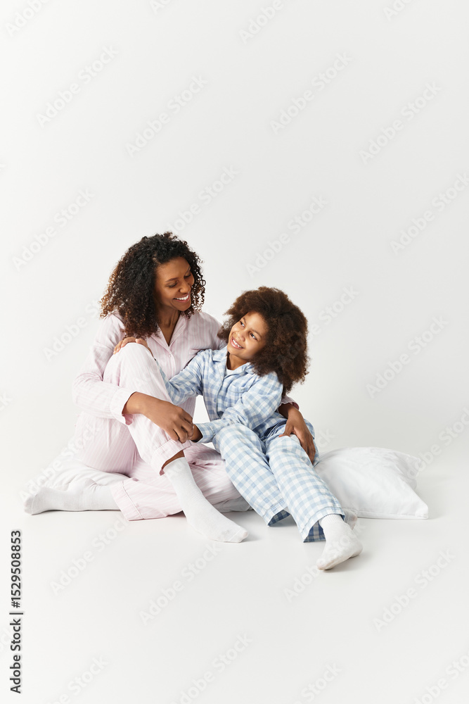 Morning cuddles African American mother and daughter in pyjamas sitting down Morning cuddles African American mother and daughter in pyjamas sitting down