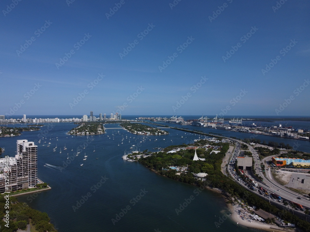Obraz premium Daytime drone view of Port of Miami and MacArthur Causeway with Biscayne Bay, ships, and Miami skyline under clear skies.