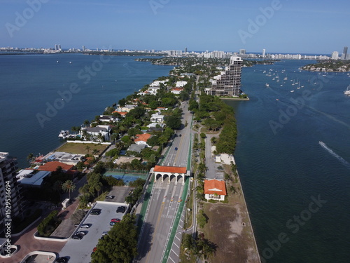 Daytime drone photo of Miami's Venetian Causeway with Biscayne Bay and city skyline under clear blue skies.