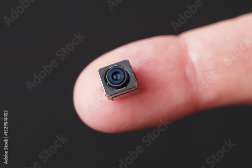 Miniature camera with tiny lens in hand, showcasing its intricate details and technology.