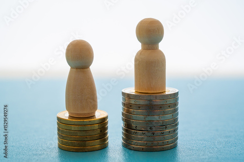 Concept of unequal pay in the workplace between men and women. Wooden figures on piles of coins.