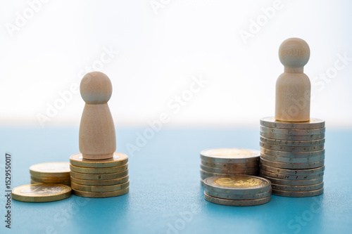 Concept of unequal pay in the workplace between men and women. Wooden figures on piles of coins.