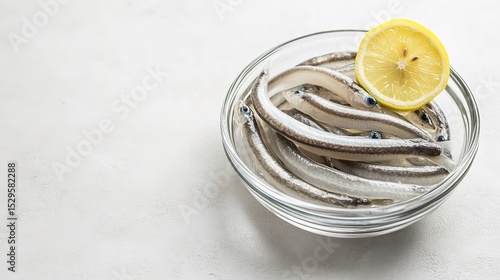 A top view of mouthwatering glass eels in a bowl with a piece of lemon on a white backdrop with plenty of room for writing, Generative AI.