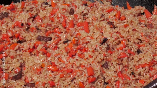 Freshly cooked pilaf in a cauldron glistens in the sun.