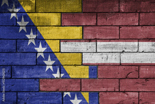 colourful painted big national flag of latvia and flag of bosnia and herzegovina on a massive old brick wall background. concept