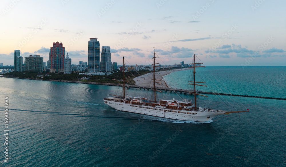Naklejka premium Sailing boat at dramatic sky seascape. Ship sailing the sea. Sail oat at port Miami. Travel by sea. Seascape horizon at sunset. Sea vacation. Sailboat vessel. Travel destination. Sail training ship