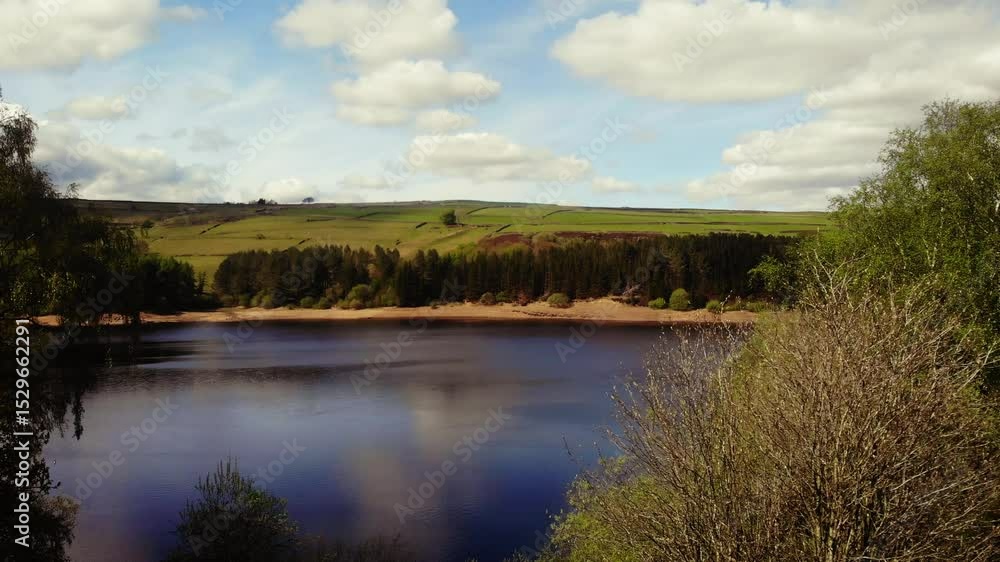 Trees and farmland surround lake in Peak District National Park blue sky Trees and farmland surround lake in Peak District National Park blue sky