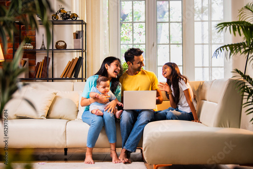 Young family using laptop indoors on sofa for shopping, surfing, and spending time together happily