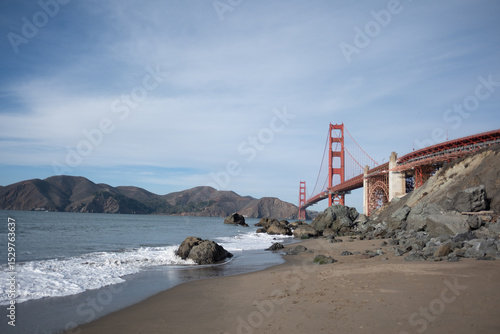 Waves crash at the beach in San Francisco, California with the Golden Gate Bridge in the background.