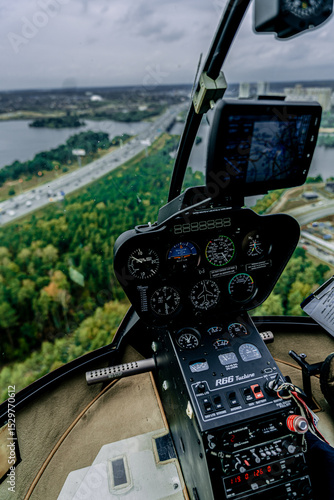 Cockpit view of Robinson R66 helicopter in flight above highway and forest
