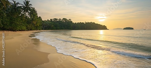 A tranquil beach at sunset with gentle waves and distant islands