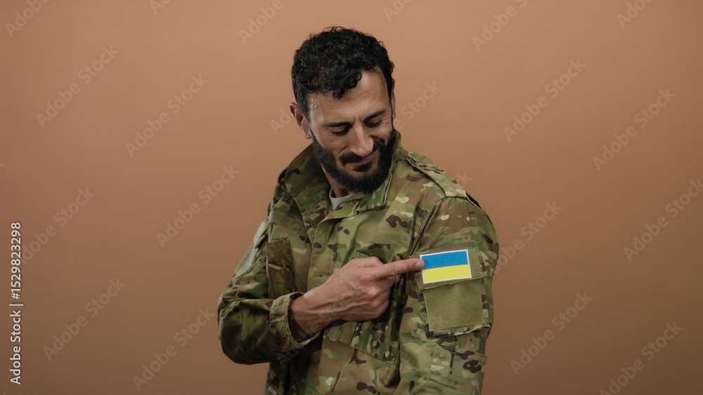 Hispanic man in military uniform with ukrainian flag patch, smiling against an orange background. Hispanic man in military uniform with ukrainian flag patch, smiling against an orange background.