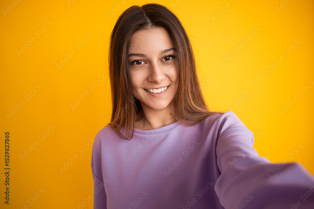 A cheerful young woman wearing a violet top smiles warmly against a bright yellow background, expressing positivity and happiness in a vivid and vibrant mood. A cheerful young woman wearing a violet top smiles warmly against a bright yellow background, expressing positivity and happiness in a vivid and vibrant mood.