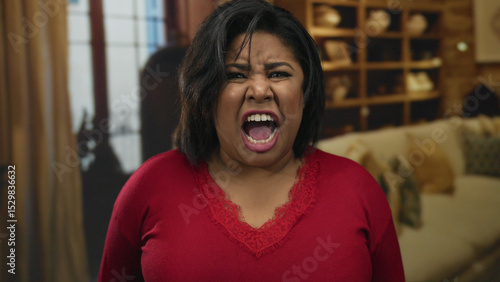 Photography Woman screaming indoors with an angry expression in a hotel room, wearing red, surrounded by homey decor, conveying emotion and intensity
