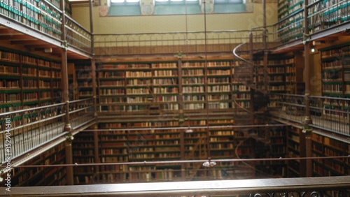 Εκτύπωση καμβά Library shelves filled with countless old books create a captivating bokeh effect in an expansive and historic reading room with multiple levels