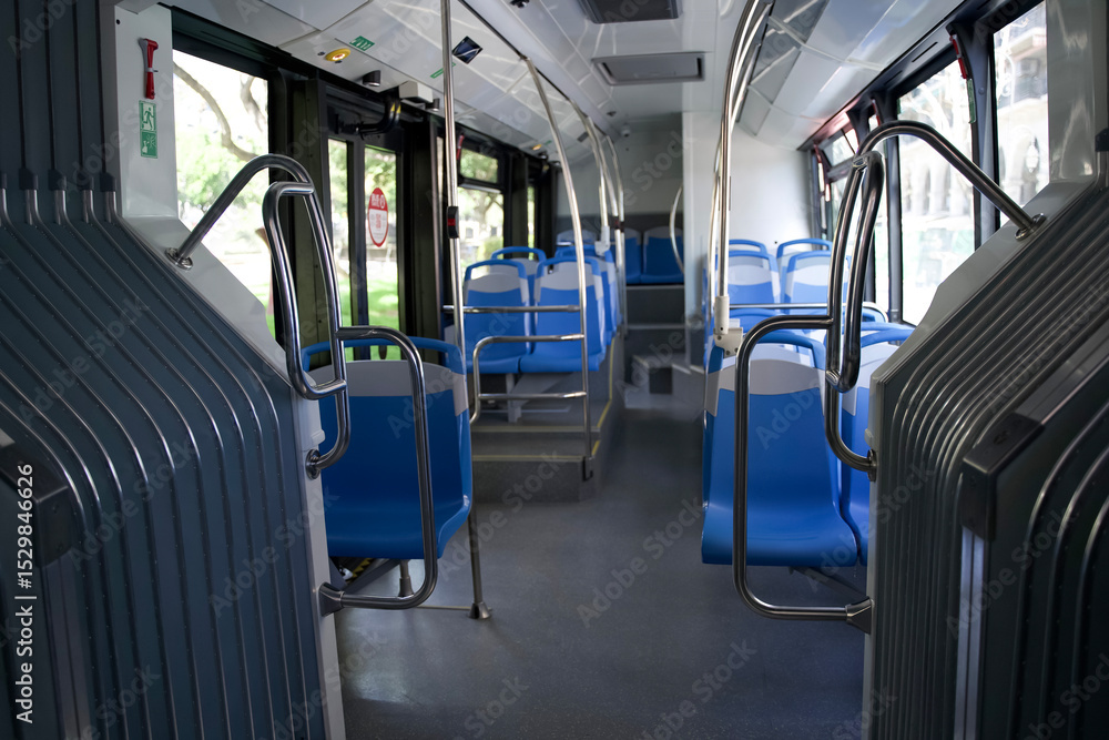 Fototapeta premium Interior of a modern city bus featuring empty blue seats and spacious layout with natural light streaming in