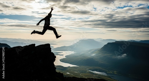 Silhouette of a person jumping off a cliff with mountains and a cloudy sky in the background scenery view